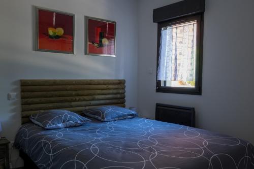 une chambre avec un lit avec des oreillers bleus et une fenêtre dans l'établissement Les Petits Bambous, à Gujan-Mestras