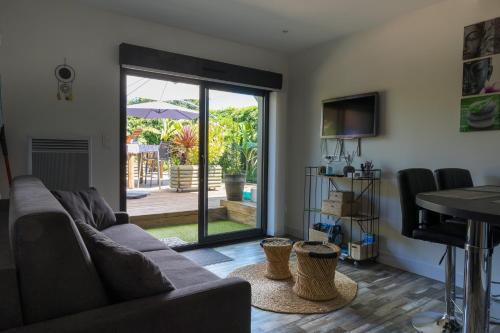 un salon avec un canapé et une porte coulissante en verre dans l'établissement Les Petits Bambous, à Gujan-Mestras