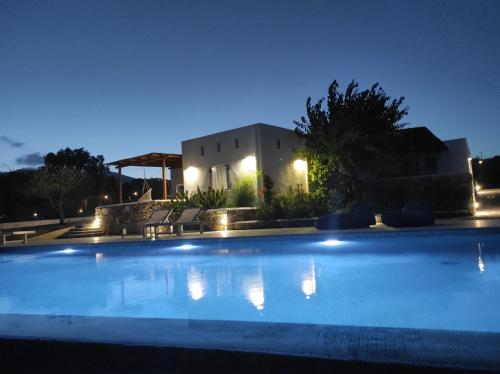 a swimming pool in front of a house at night at Andria's suites in Chrissi Akti