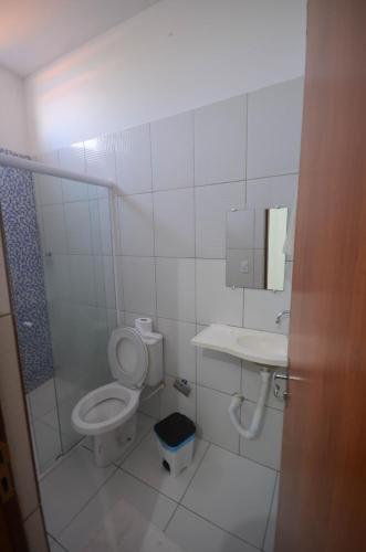 a white bathroom with a toilet and a sink at Pousada Central in Barreirinhas