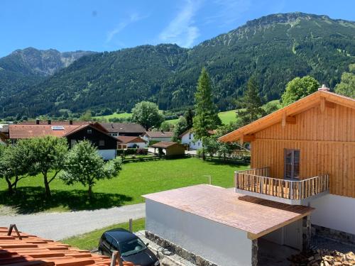 Vistas a una casa con montañas en el fondo en Landhaus „Divija Haus“ Ferienwohnung en Pfronten