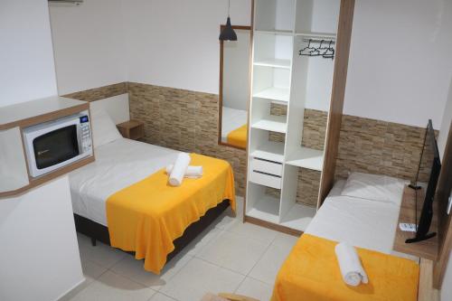 um pequeno quarto com duas camas e uma tv em Nosso Cantinho Canasvieiras em Florianópolis