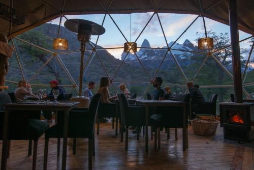 restauracja z ludźmi siedzącymi przy stolikach przed dużym oknem w obiekcie Patagonia Eco Domes w mieście El Chaltén