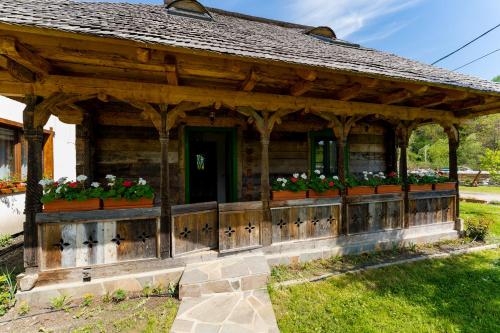 a wooden pavilion with flowers on it in a yard at Pensiunea Casa Traditiilor in Ieud