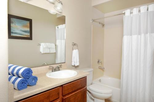 a bathroom with a sink and a toilet and a mirror at Raintree at Phoenix South Mountain Preserve in Phoenix