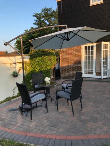 une terrasse avec une table, des chaises et un parasol dans l'établissement Peaceful 3 Bed Home, à Basildon