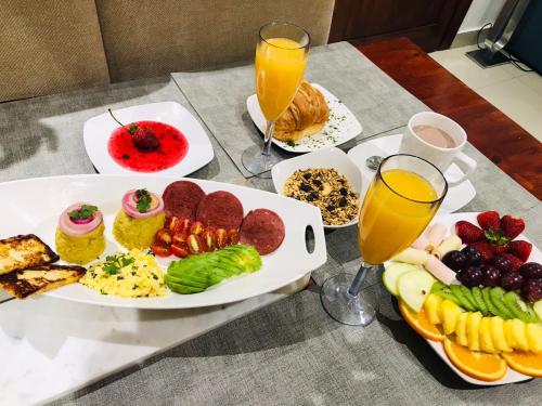 a table with plates of food and glasses of orange juice at Torre Real IV L3 Santiago DR con cocinero para desayuno in Santiago de los Caballeros