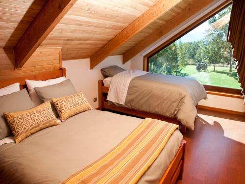 two beds in a room with a window at Cabañas Patagonia Lefun in Pucón