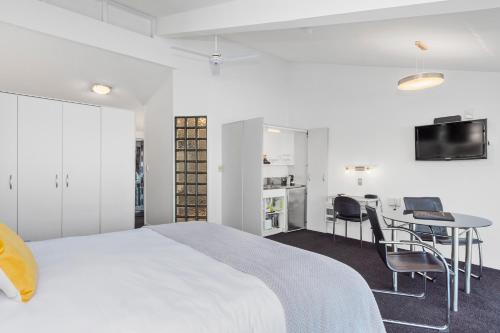 a bedroom with a bed and a desk and a tv at The Tauranga on the Waterfront in Tauranga
