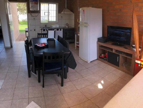 a kitchen with a black table and chairs and a refrigerator at Cabaña Bello Horizonte, 3 5 3 5 0 8 5 9 0 6 ,dos dormitorios con cochera privada doble, asador y parque in Villa María