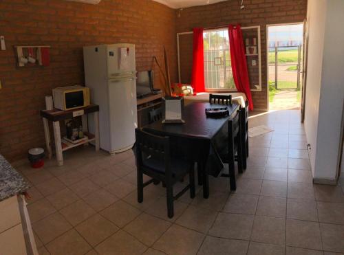 a kitchen with a table and chairs and a refrigerator at Cabaña Bello Horizonte, 3 5 3 5 0 8 5 9 0 6 ,dos dormitorios con cochera privada doble, asador y parque in Villa María