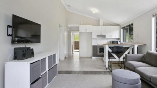 a white living room with a couch and a kitchen at Free Spirit in Metung - near the Hotsprings and Golf Course in Metung