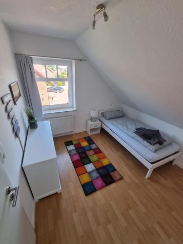 Habitación con cama, ventana y alfombra. en Oberdeck, en Neuharlingersiel
