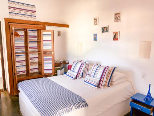 a bedroom with a white bed with striped pillows at La Maison de Vacances in Búzios
