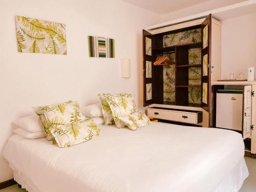 a bedroom with a white bed with pillows at La Maison de Vacances in Búzios