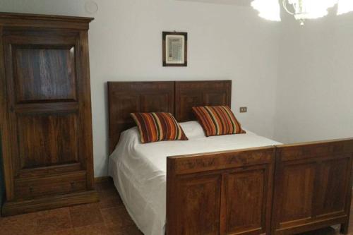1 dormitorio con 1 cama de madera y 2 almohadas en Borgo Scorza 2, en Pietramogolana