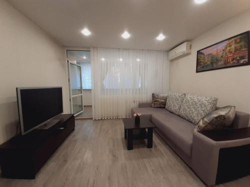 a living room with a couch and a flat screen tv at Sun City apartment 1 in Sochi