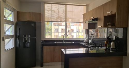 a kitchen with a black refrigerator and a window at Departamento en condominio con alberca y área infantil in Manzanillo