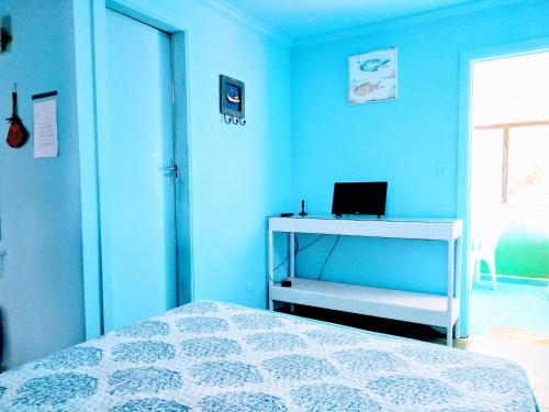 a bedroom with a bed and a desk with a laptop at Residencial Praia Bertioga Pé na Areia in Bertioga