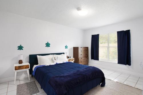 sypialnia z niebieskim łóżkiem i oknem w obiekcie Cozy Home Minutes Away From Disney w mieście Kissimmee