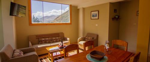 ein Wohnzimmer mit einem Tisch, Stühlen und einem Fenster in der Unterkunft Departamentos Bellavista La Alborada Huaraz in Huaraz