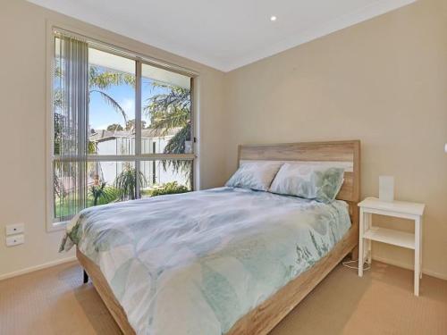 a bedroom with a bed and a large window at Pool in Paradise by Experience Jervis Bay in Vincentia