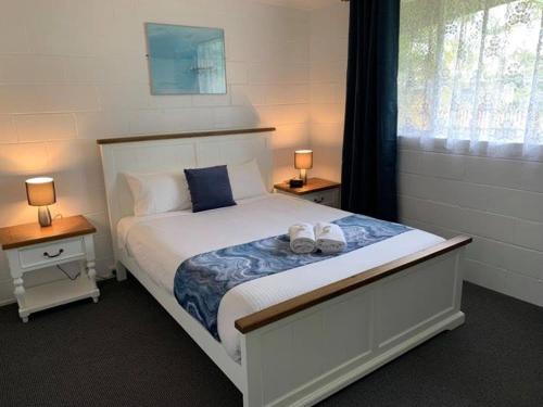 una camera da letto con un grande letto bianco con due lampade di Leisure Tourist Park a Port Macquarie