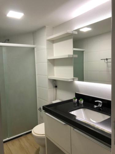 a bathroom with a sink and a toilet and a mirror at Flat Beira Mar de Tambaú apto 206 in João Pessoa