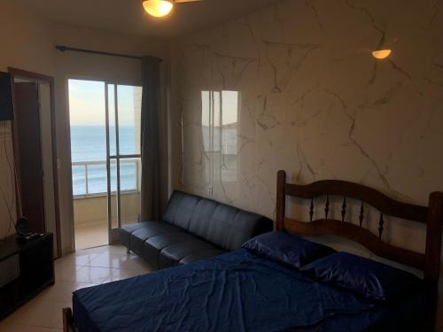 1 dormitorio con cama, sofá y ventana en Apartamento Guarapari Luxo Frente para o Mar, en Guarapari