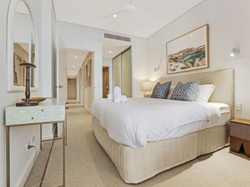 a white bedroom with a large bed and a table at The Watermark by Experience Jervis Bay in Huskisson