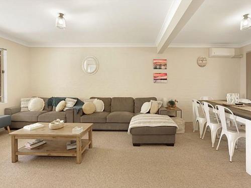 a living room with a couch and a table at Burrill by the Beach by Experience Jervis Bay in Huskisson