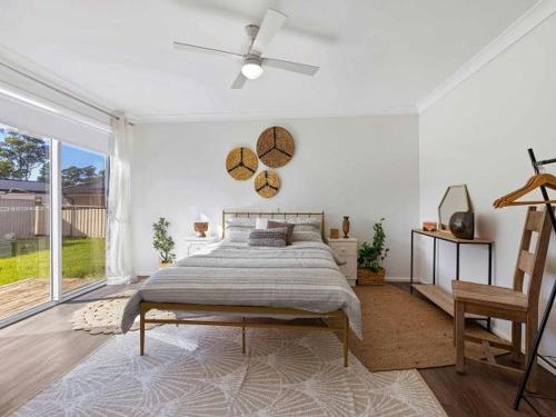 a bedroom with a bed and a large window at Centaur Sanctuary by Experience Jervis Bay in Sanctuary Point