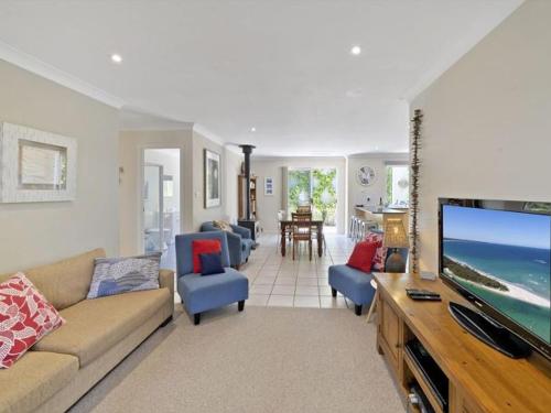 a living room with a couch and a tv at Husky House by Experience Jervis Bay in Huskisson
