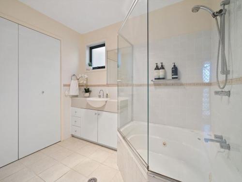 a white bathroom with a shower and a sink at Portside at The Arc by Experience Jervis Bay in Vincentia