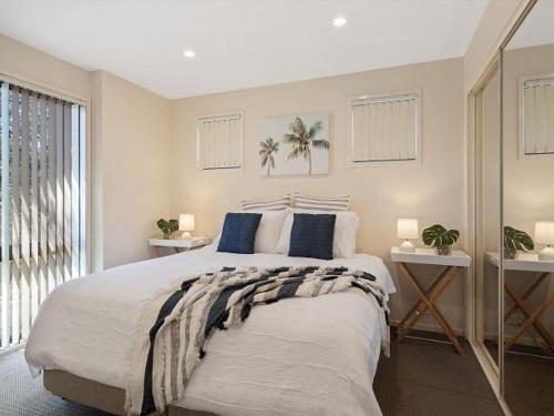 1 dormitorio con 1 cama grande con almohadas azules en Portside at The Arc by Experience Jervis Bay, en Vincentia
