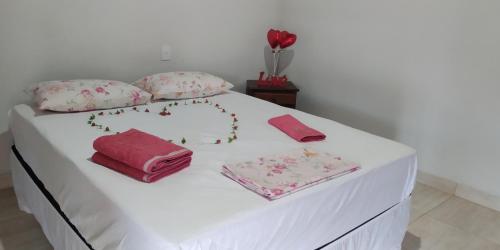 a white bed with pink sheets and pillows on it at Suite independente em casa de fazenda in Capitólio