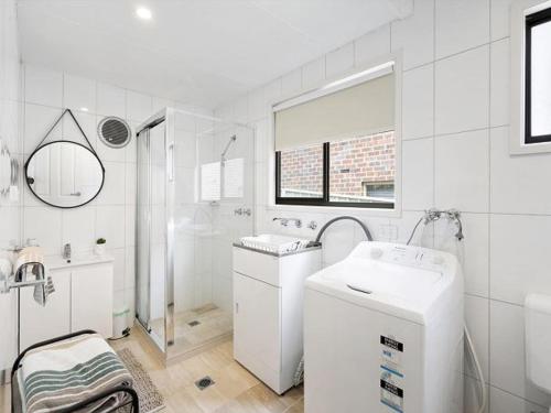 a white bathroom with a sink and a washing machine at The Shack by Experience Jervis Bay in Vincentia
