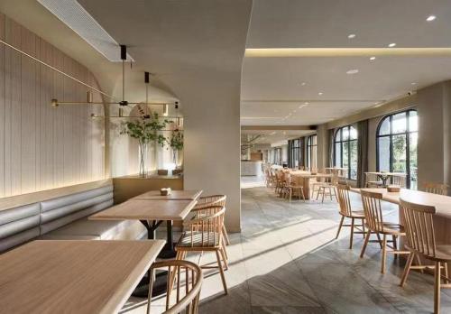 a restaurant with wooden tables and chairs and windows at Ebo Hotel in Hangzhou