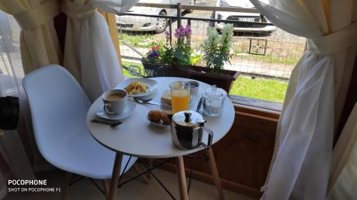 einen weißen Tisch mit einem Frühstück mit Kaffee und Orangensaft in der Unterkunft Paraiso Patagonico in Chaitén