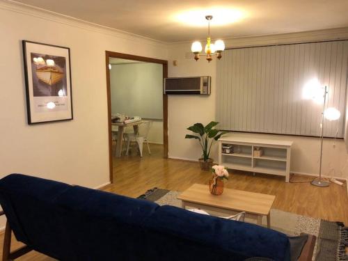 キャンベルタウンにあるCAMPBELLTOWN HOLIDAY HOME 3 BED + FREE PARKING NCA039の青いソファとテーブルのあるリビングルーム