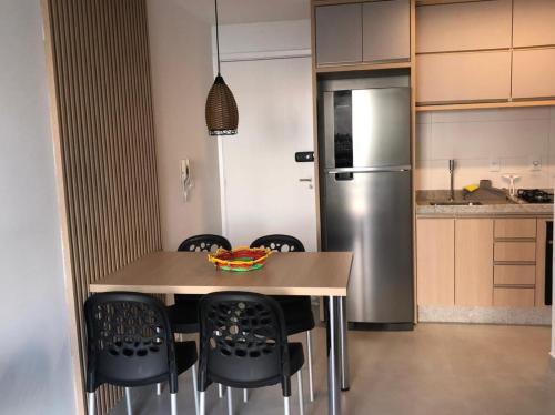 eine Küche mit einem Tisch mit Stühlen und einem Kühlschrank in der Unterkunft Muro Alto Condomínio Clube in Porto De Galinhas