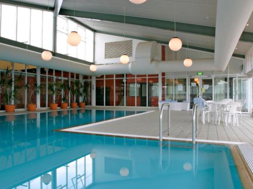 a swimming pool in a building with chairs and plants at Horizons 501 in Jindabyne