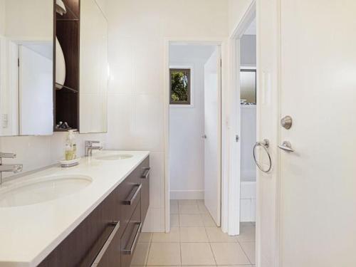 a white bathroom with two sinks and a shower at Alva Lee by Experience Jervis Bay in Vincentia