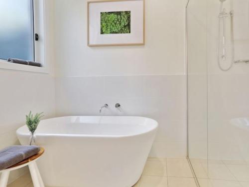 a white bathroom with a tub and a shower at Banksia on Blenheim by Experience Jervis Bay in Vincentia