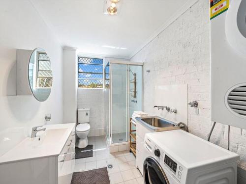 a white bathroom with a washing machine in it at Vincentia Retreat by Experience Jervis Bay in Vincentia