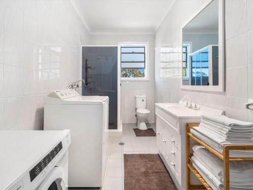 un bagno bianco con lavandino e WC di Vincentia Breeze by Experience Jervis Bay a Vincentia