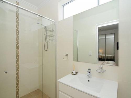 a white bathroom with a sink and a shower at Bombara by Experience Jervis Bay in Huskisson