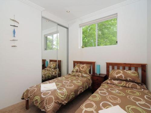 a bedroom with two beds and a mirror at Bombara by Experience Jervis Bay in Huskisson