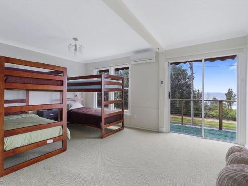 a bedroom with two bunk beds and a balcony at Summer Breeze by Experience Jervis Bay in Vincentia