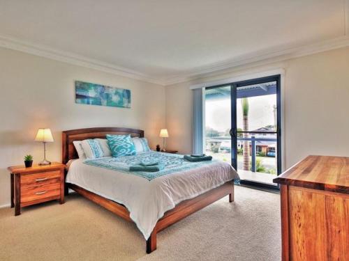 a bedroom with a bed and a large window at Benjos by Experience Jervis Bay in Vincentia